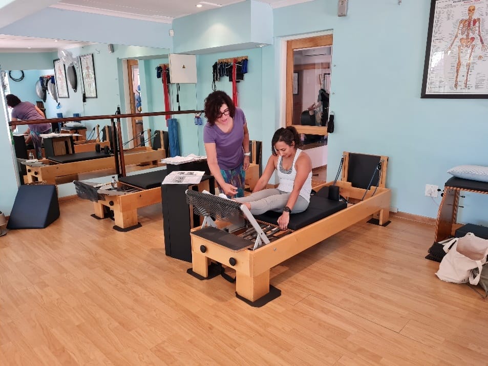 pilates bench Pilates Instructor guiding student using pilates bench